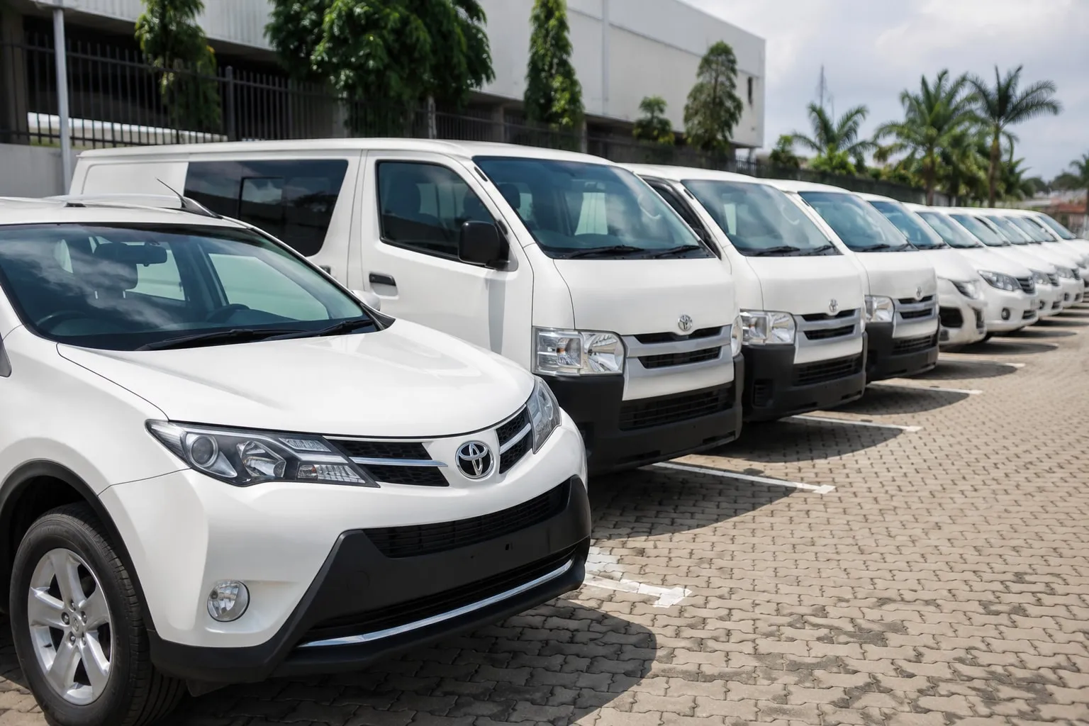 A row of white SUVs and vans parked at a company depot.